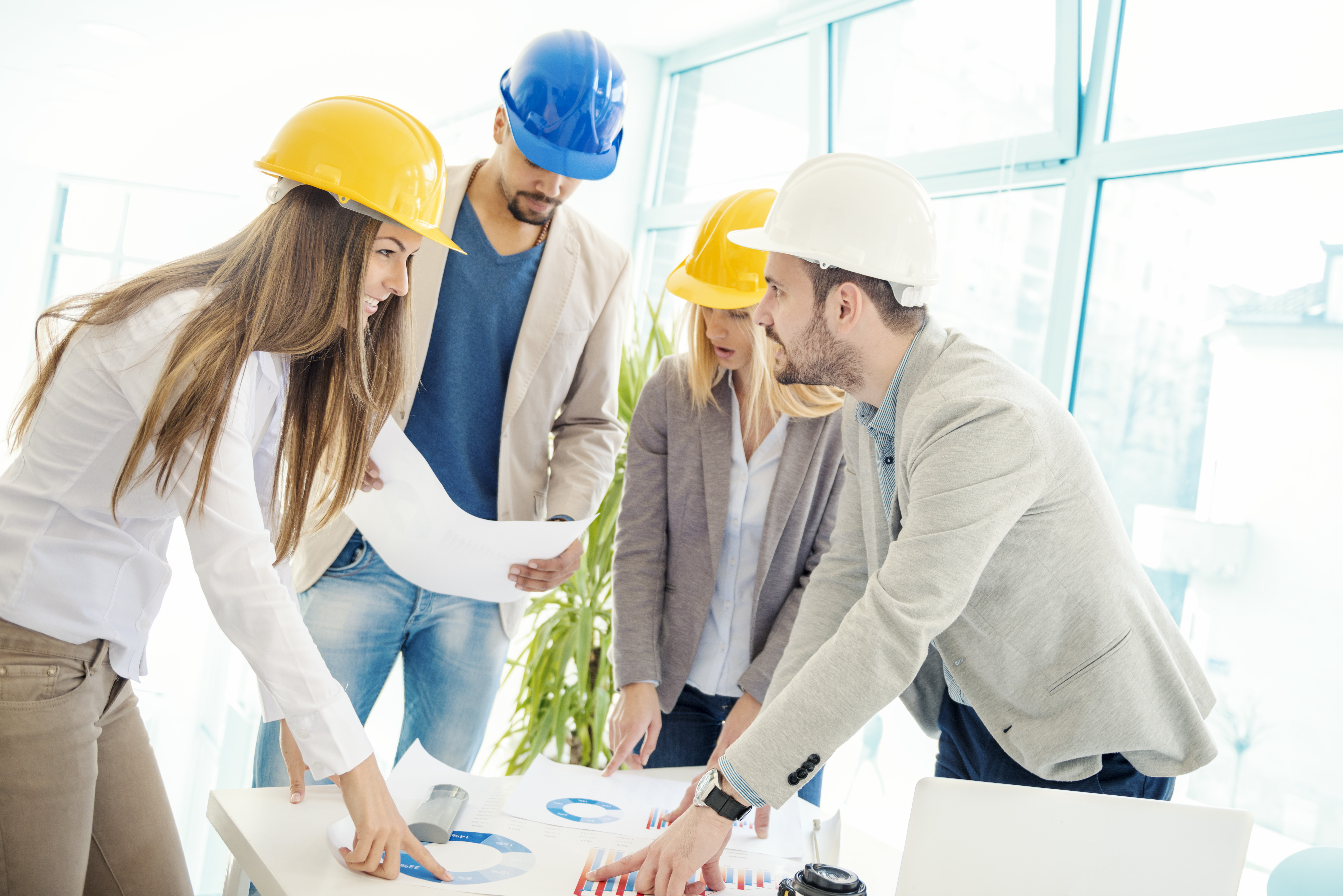 Image of four successful business partners working at meeting in office.Construction workers checking the architectural plans before they start the building project.